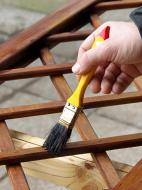 Terrassenholzöl Mann streicht Gartenzaunelement